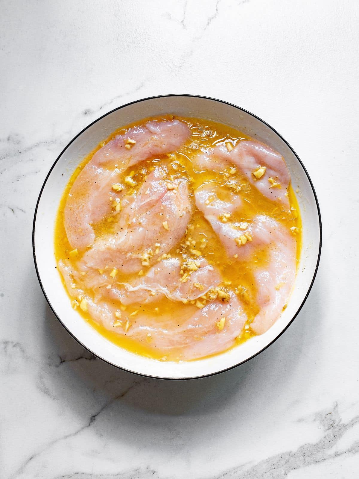 chicken cutlets in a bowl of marinade
