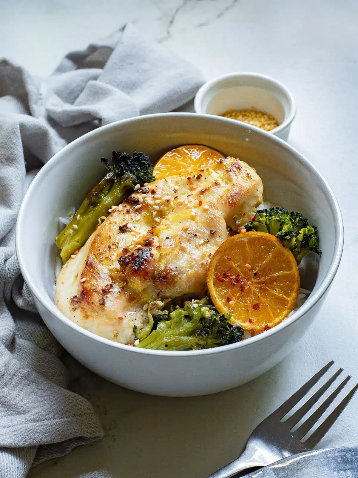 White bowl filled with sheet pan chicken cutlets and broccoli over rice