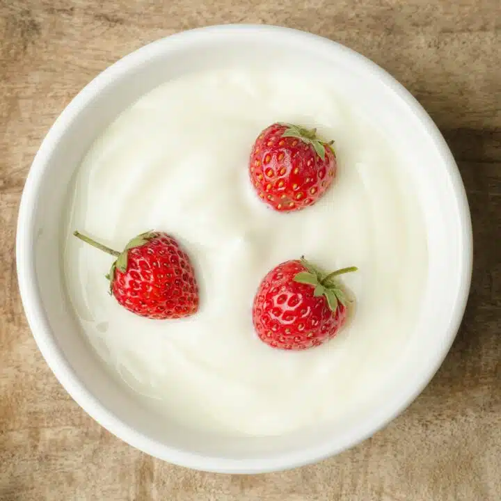Bowl of homemade yogurt with whole strawberries.