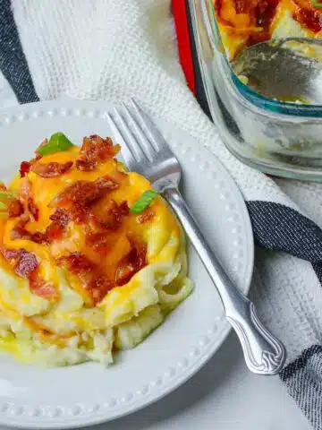 mashed potatoes with cheese and bacon on white plate.