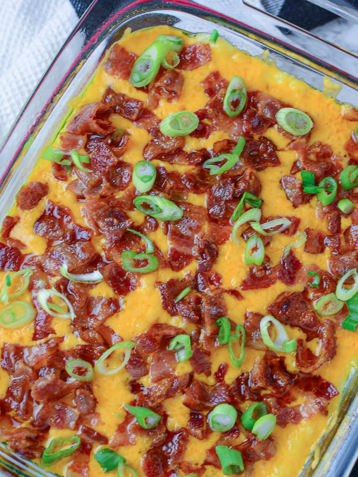 Baked mashed potato casserole with cheese, bacon and green onions on top.