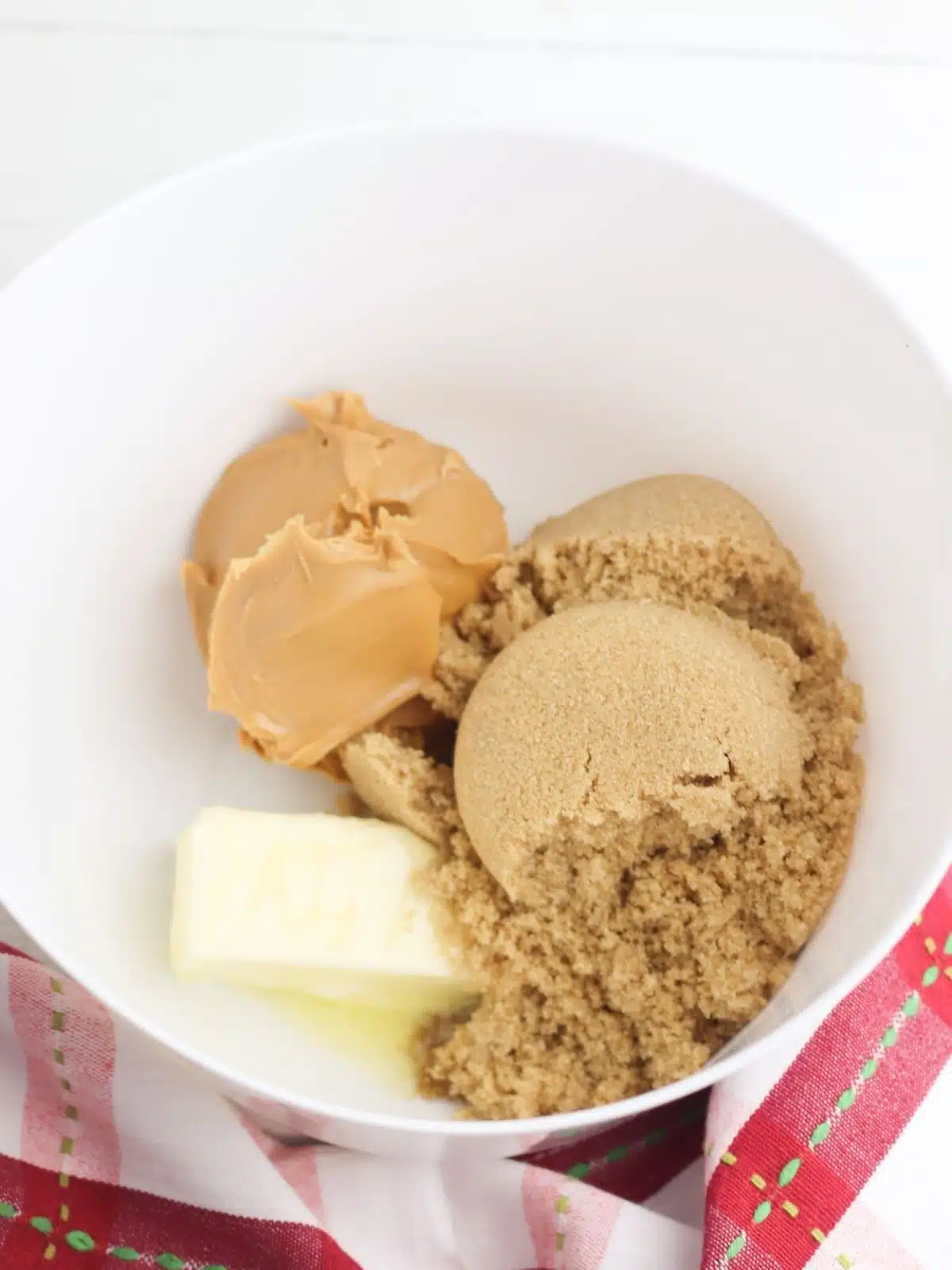 brown, white sugar with peanut butter and butter in bowl.