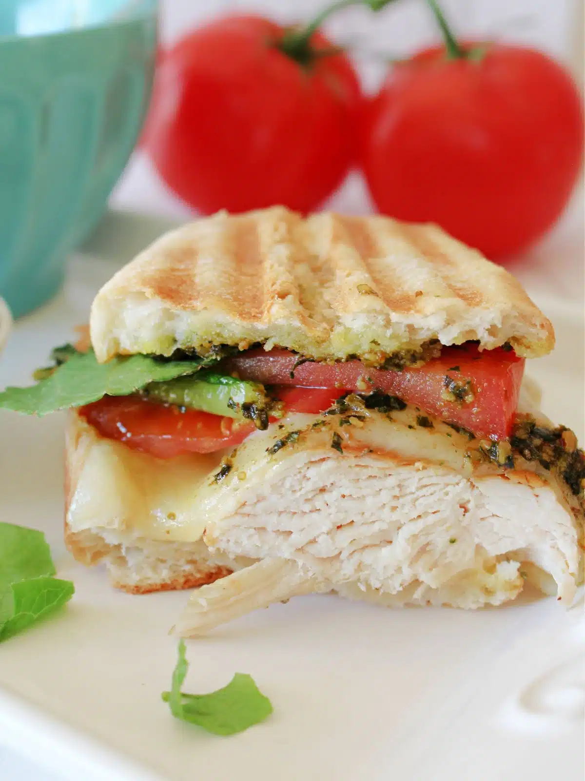 Close up of the chicken cutlet sandwich with whole tomatoes in the background.