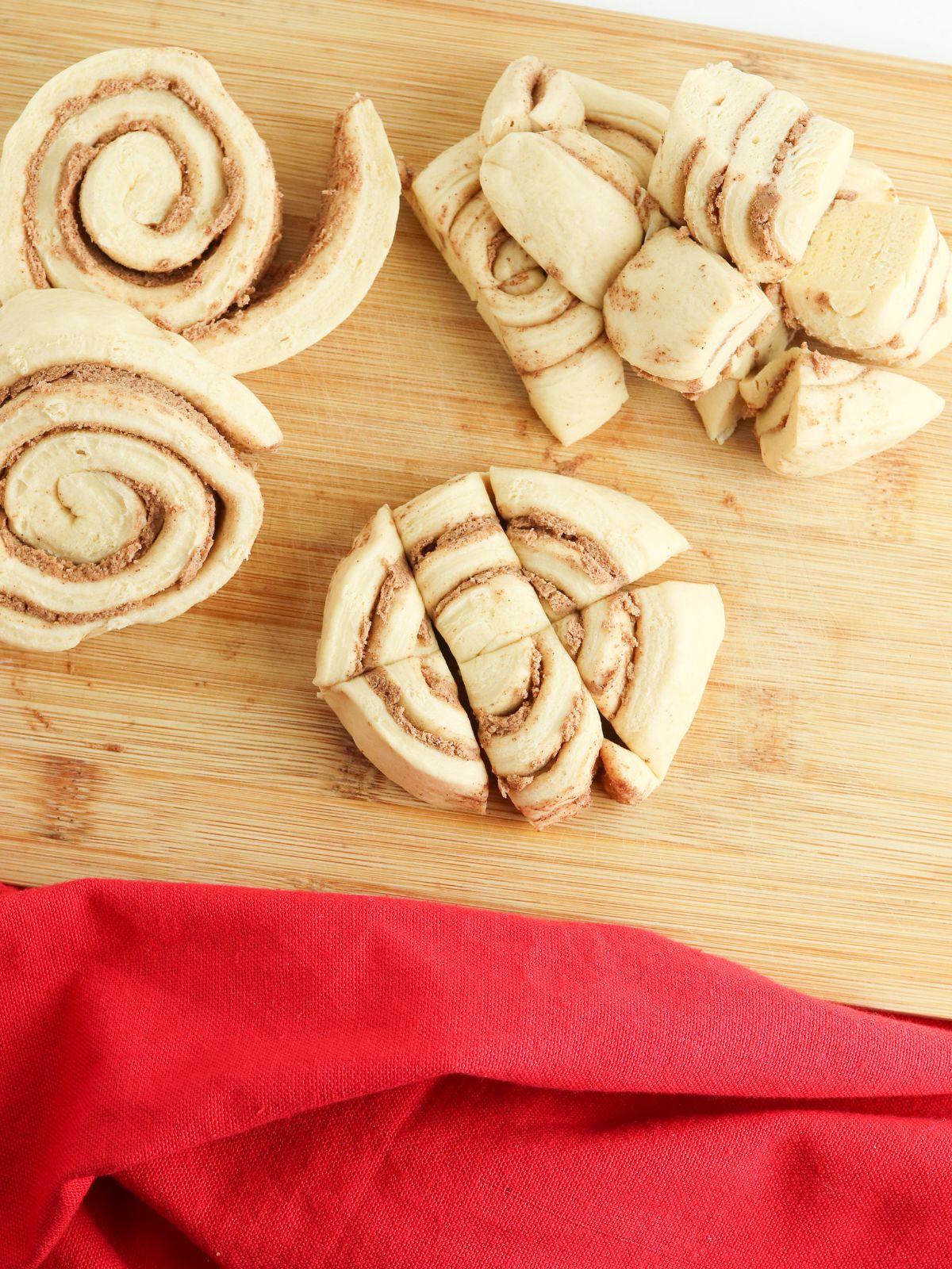 Sliced up cinnamon rolls on a wooden cutting board