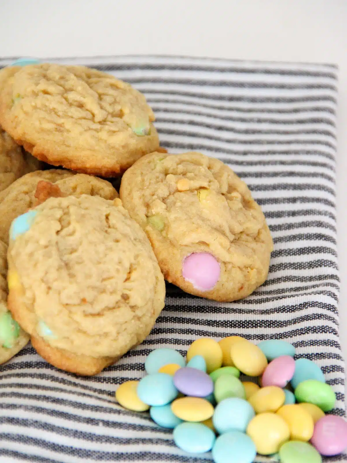 Easter cookies with M&M candies stacked on dish towel.