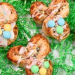 Bunny Cinnamon Rolls decorated with icing and M&M's on white tray with green paper grass.