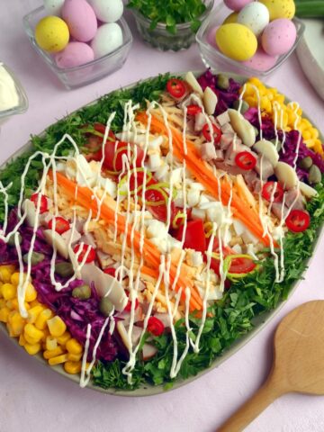 salad with tomatoes, corn, red cabbage, ham, lettuce and salad dressing.