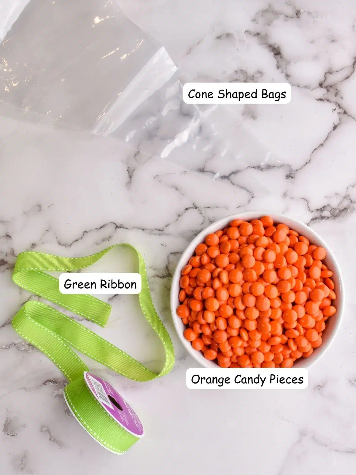 cone shaped bags, green ribbon and orange candy pieces in bowl.
