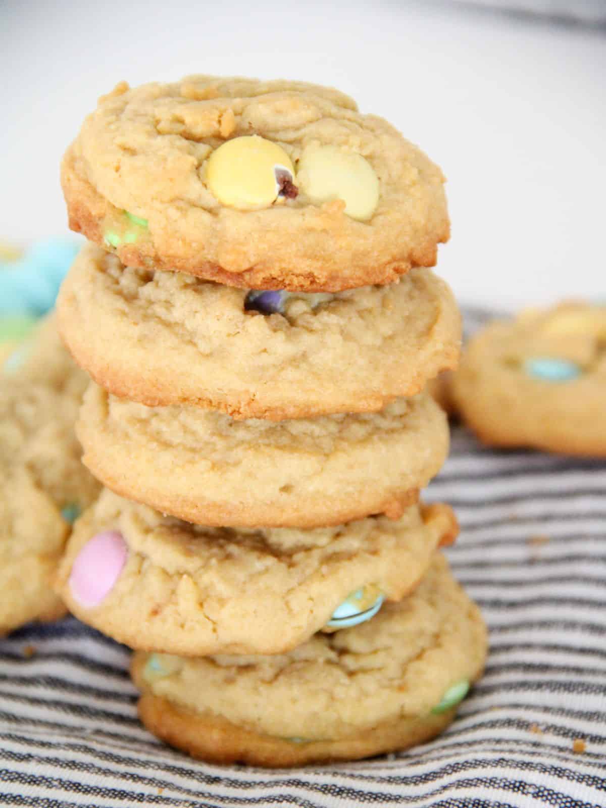 Easter cookies stacked on black and white striped dish towel.