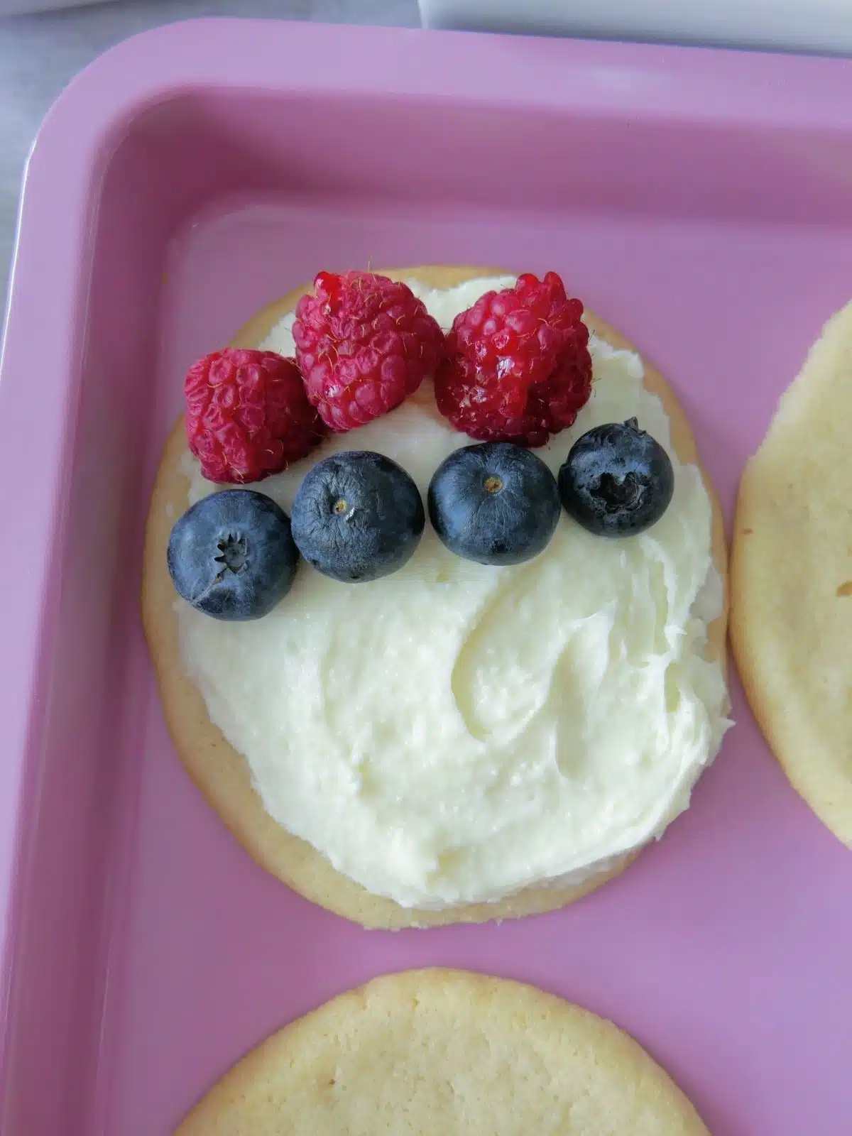 egg shaped cookie with frosting, blueberries and raspberries.