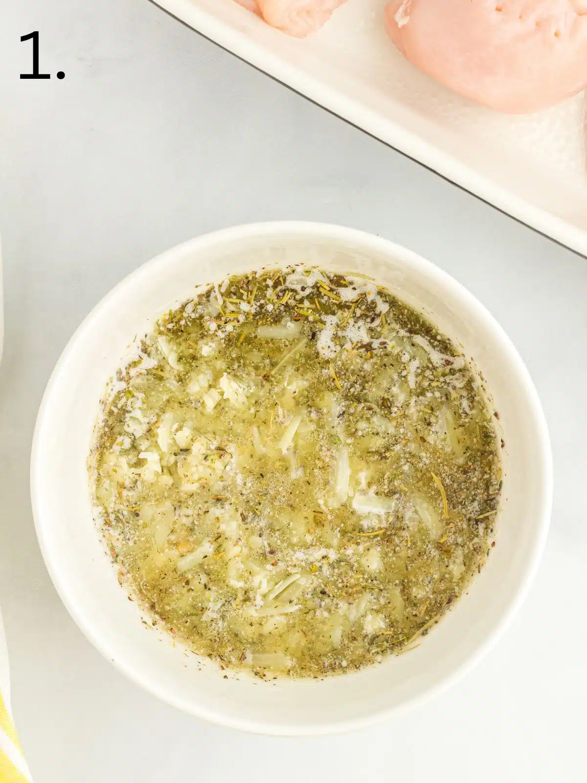melted butter with herbs and garlic in small white bowl.