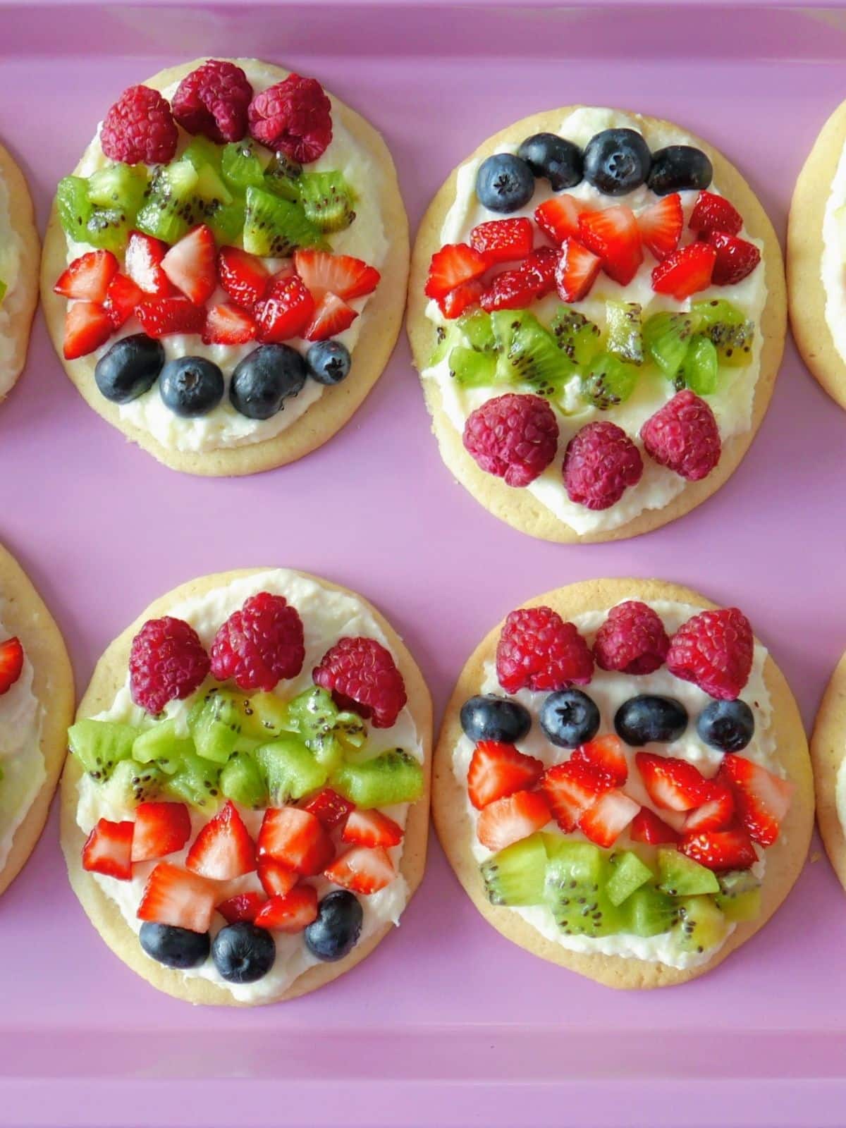 egg shaped mini fruit pizzas on pink tray.