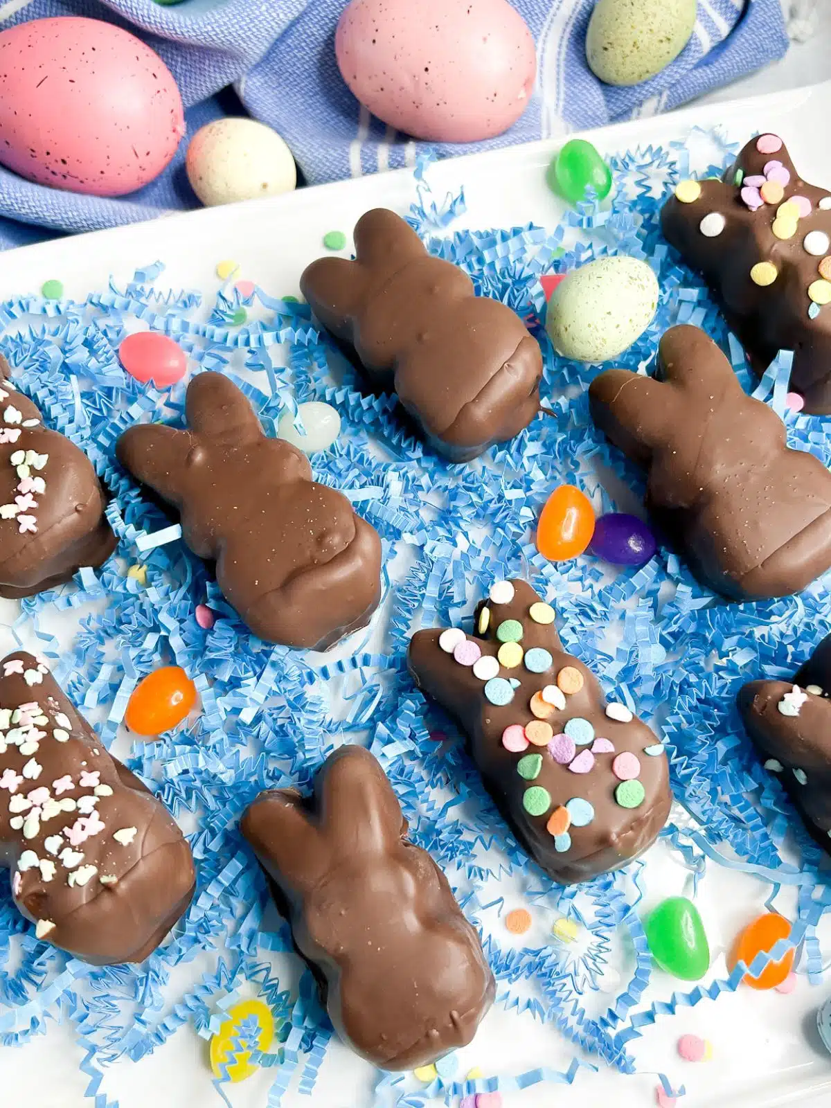 Plate full of chocolate dipped marshmallow Peeps with blue confetti.