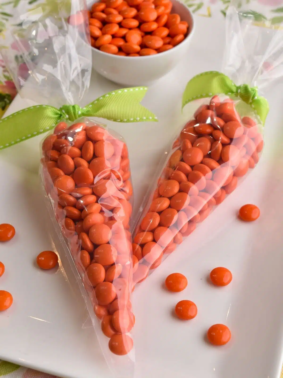 cellophane bags filled with orange candy pieces tied with green ribbon for Easter no bake treats.