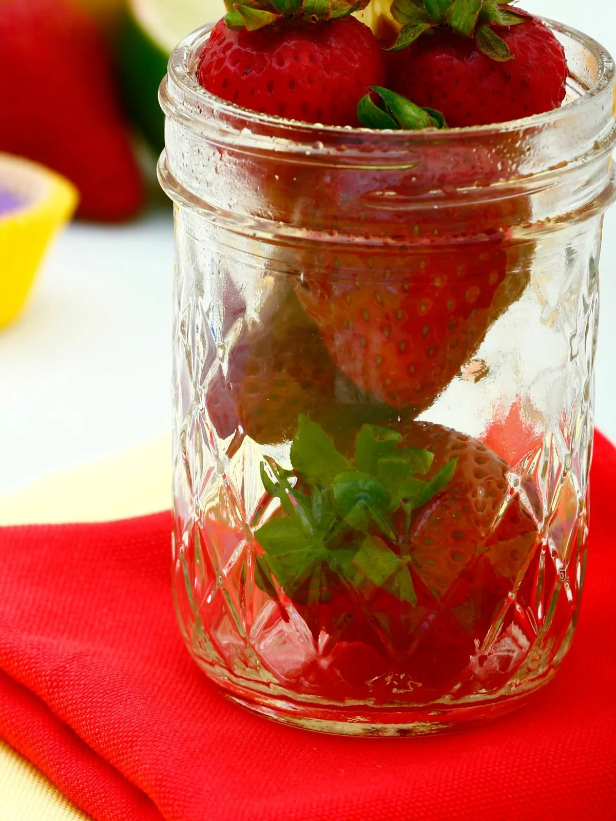 Strawberries in mason jar on red cloth.