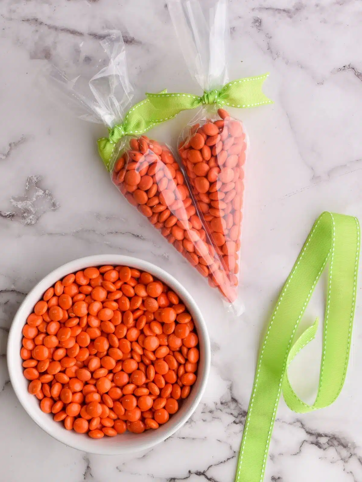 bowl or orange candy pieces, green ribbon and cone shaped plastic bags filled with orange candy and tied with ribbon.