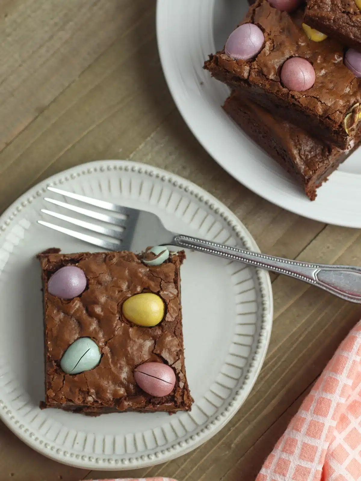 homemade brownies with candy eggs on white plate with fork.