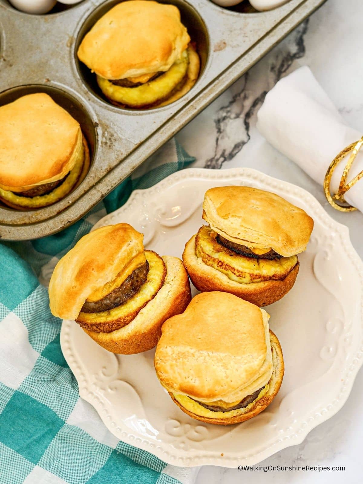 biscuits with eggs, sausage and cheese baked on white plate.