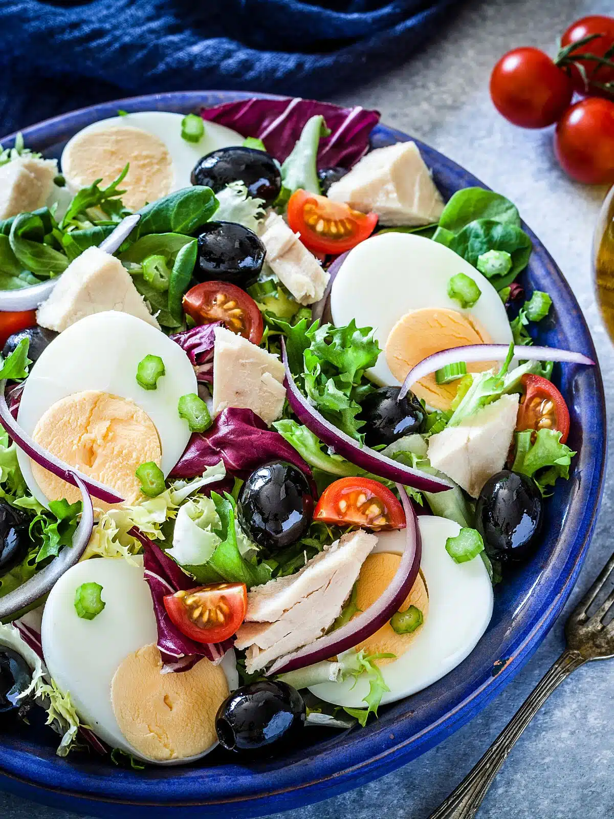 Salad with hard boiled eggs, black olives, red onion and tomatoes.