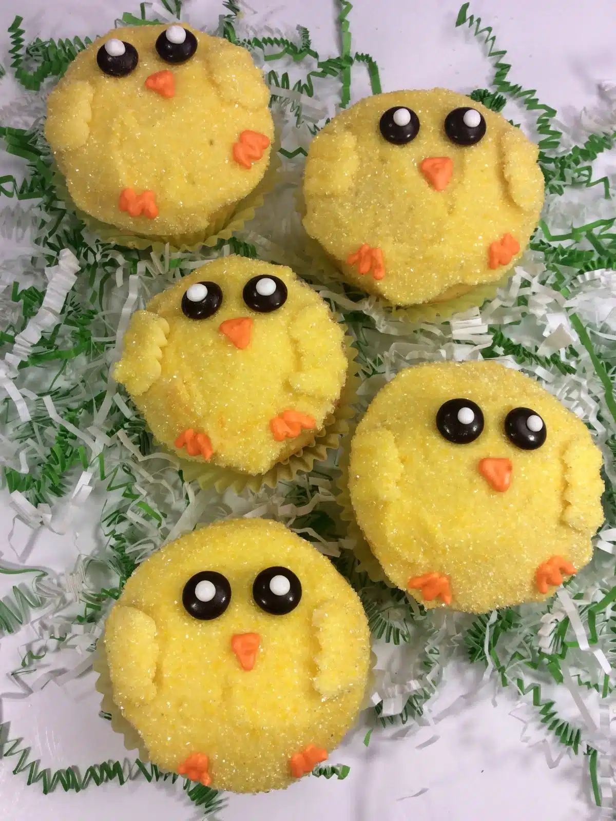 Chick cupcakes on top of green shredded paper.