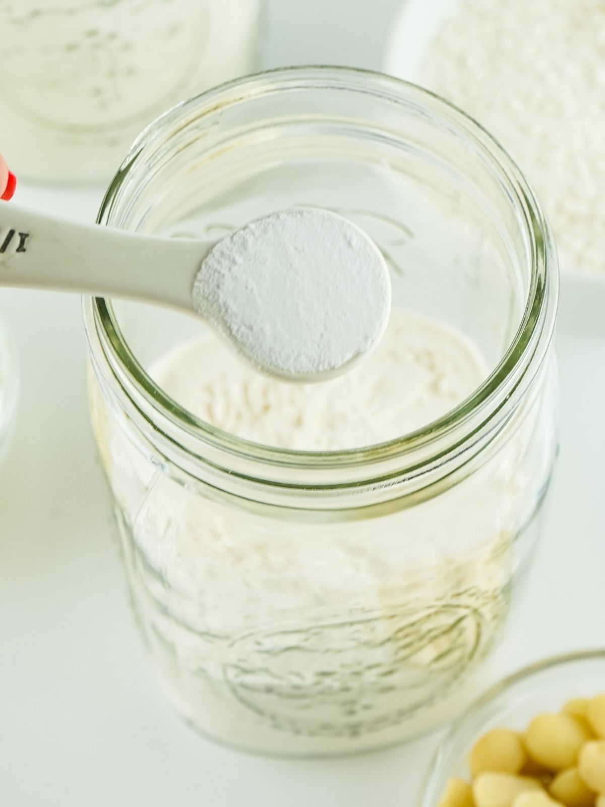 Adding teaspoon of baking soda to dry ingredients in mason jar.