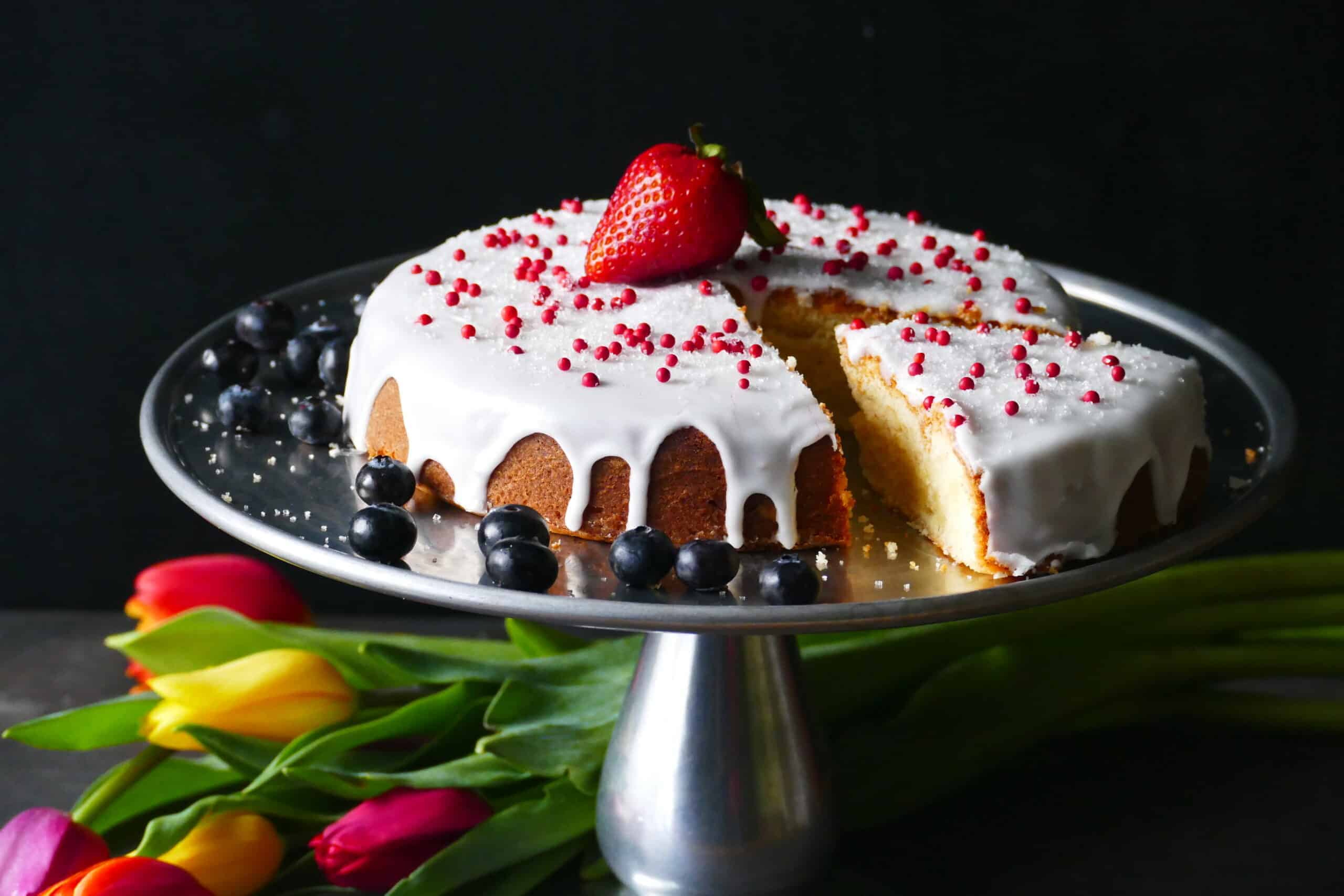round cake with white frosting dripping down sides.