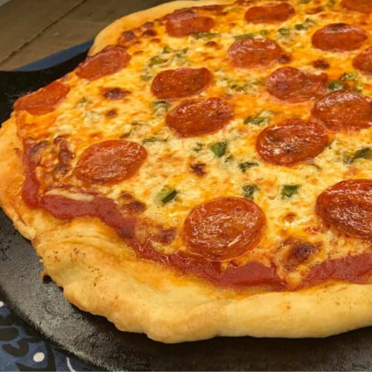 homemade pizza on pizza stone with pepperoni and green pepeprs.