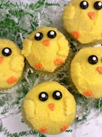 cupcakes decorated as Easter chicks on white platter.