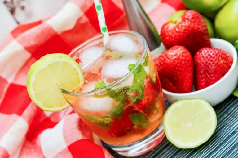 a glass of strawberry mojito with lime and mint.