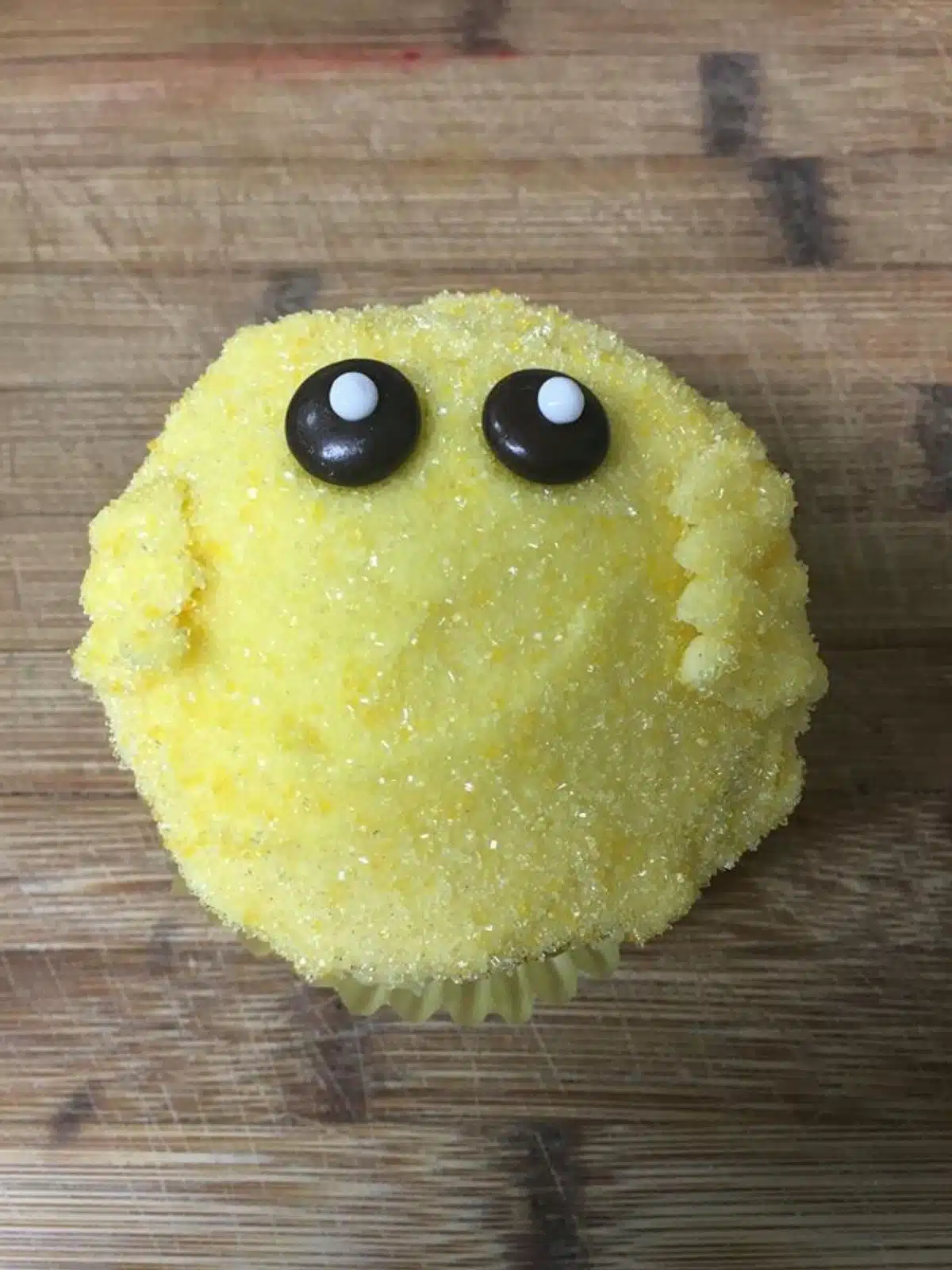 Chick cupcake decorated with black eyes.