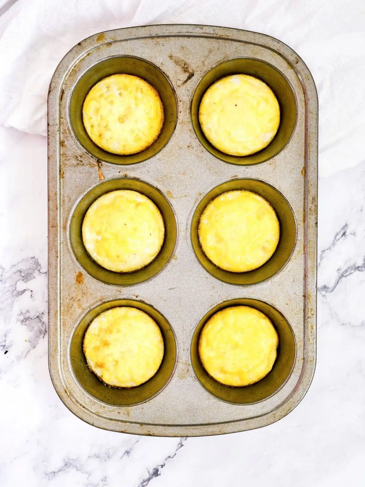 cooked eggs on top of biscuits in muffin pan.