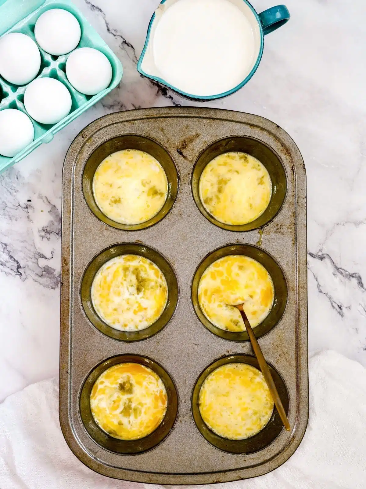 Add raw eggs to muffin pan.