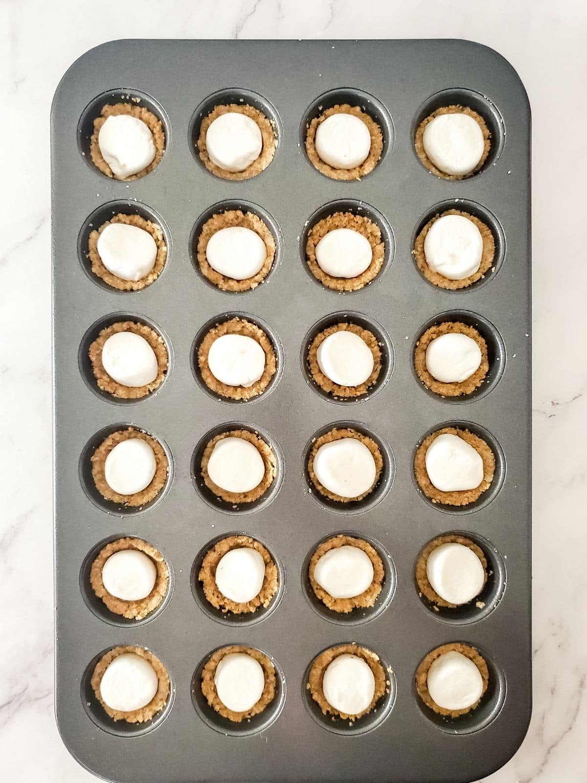 Add marshmallows on top of graham cracker cup in muffin pan.