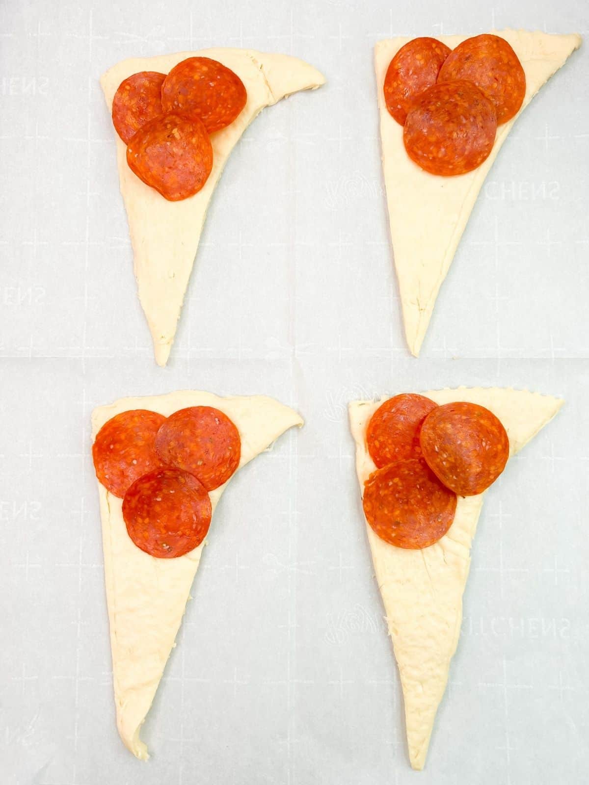 pepperoni slices on raw dough crescent roll triangles.