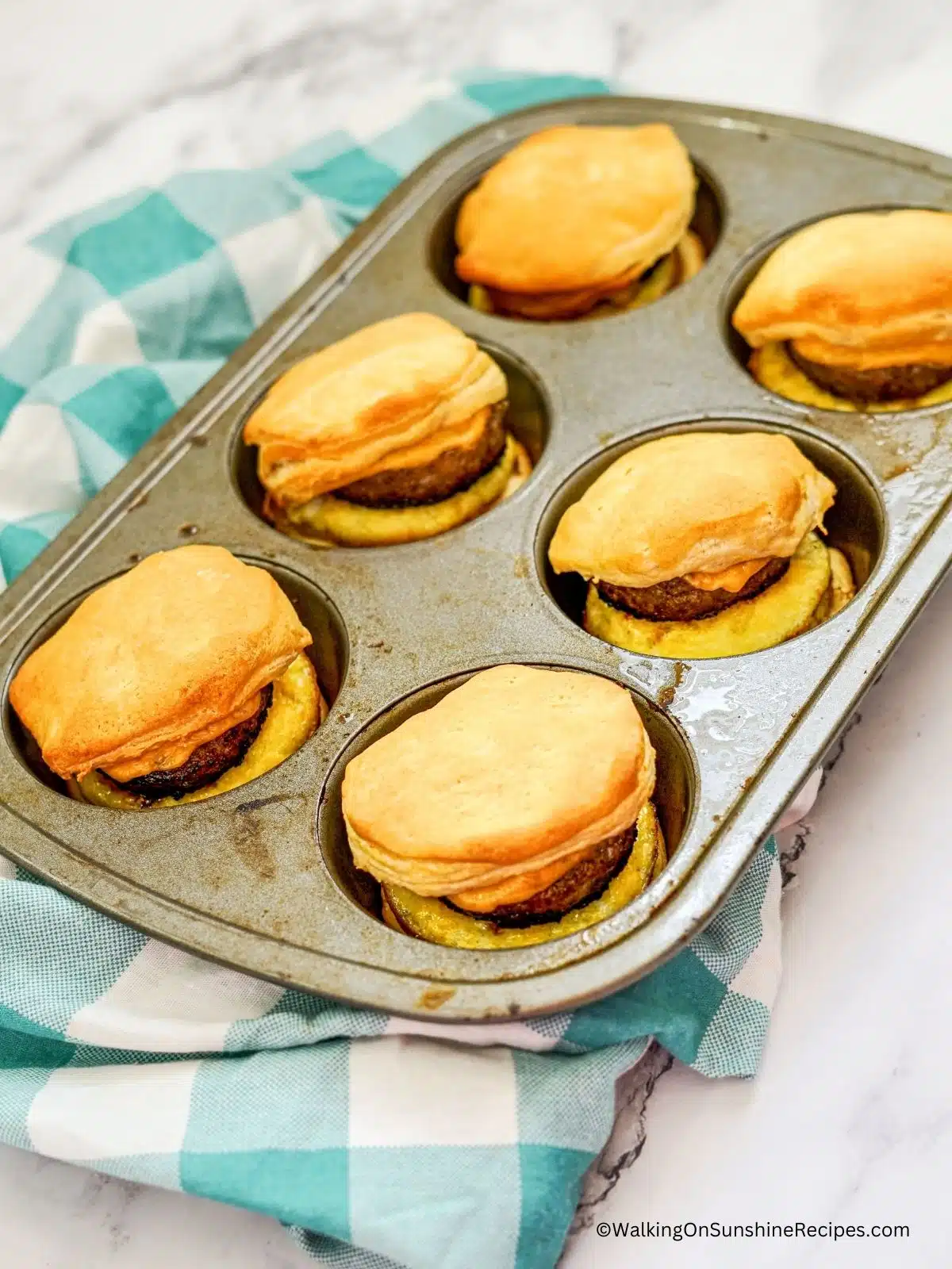 Baked biscuits with eggs, sausage and cheese in muffin pan.