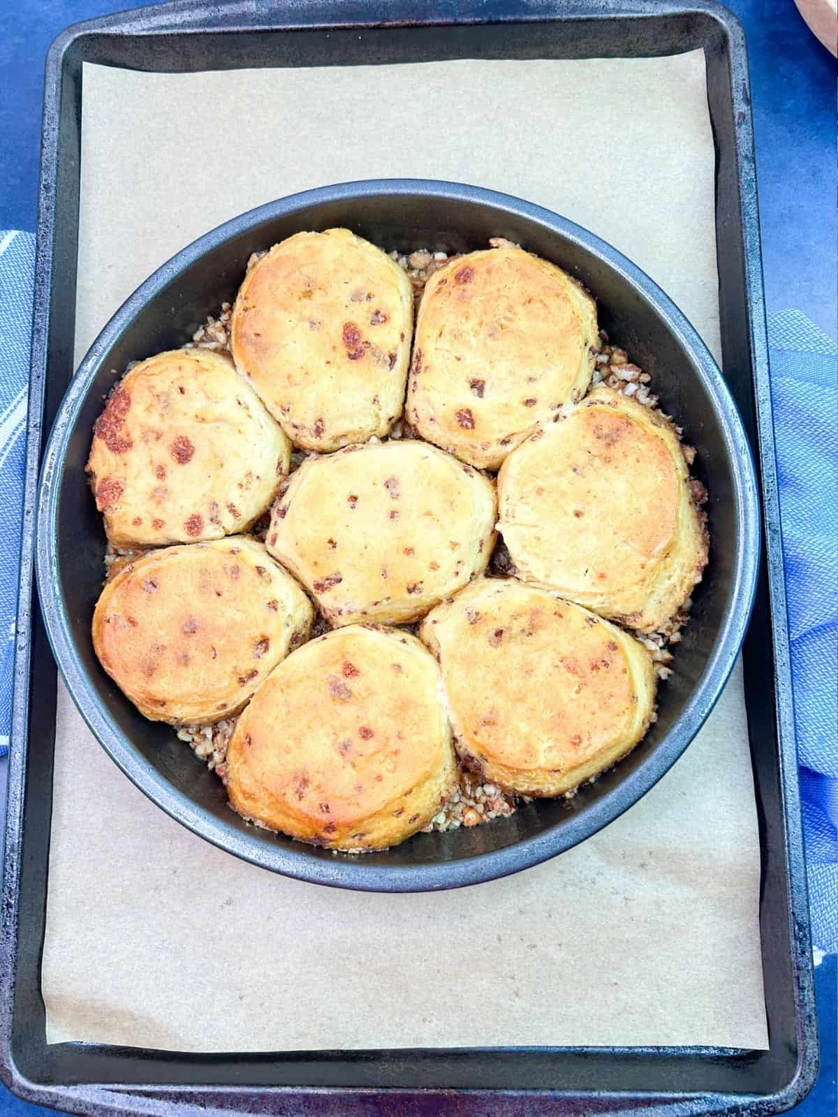 baked canned cinnamon rolls on top of pecan topping in cake pan.