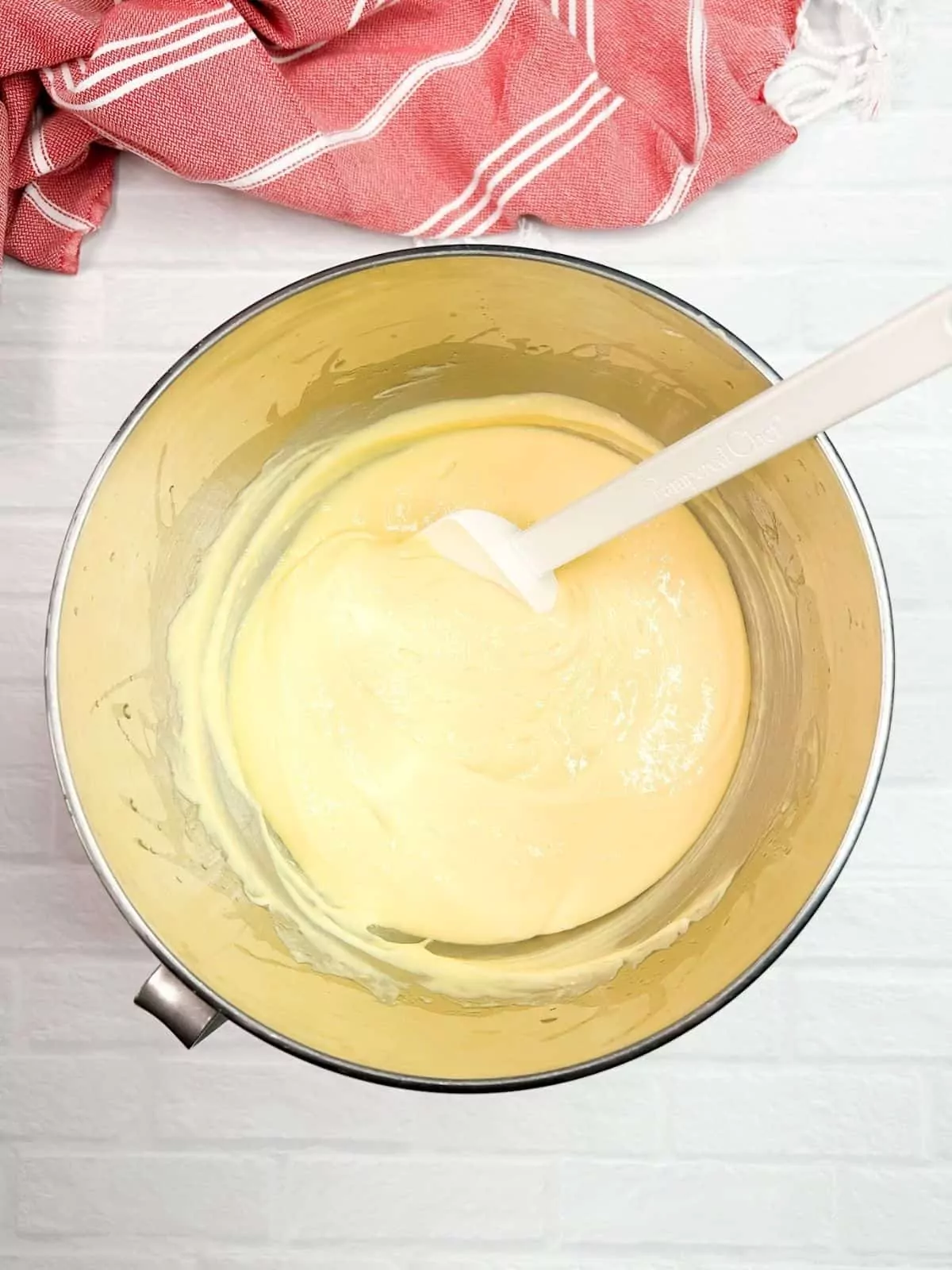 vanilla cake batter in mixing bowl with rubber spatula.