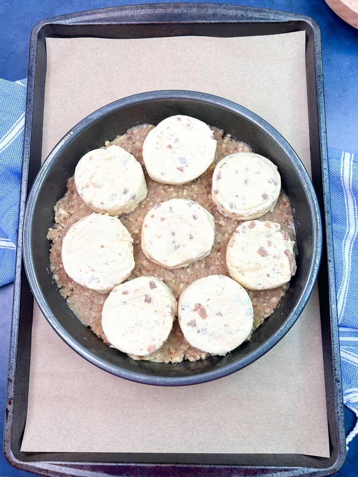 canned cinnamon rolls on top of homemade pecan sugar toping in cake pan.