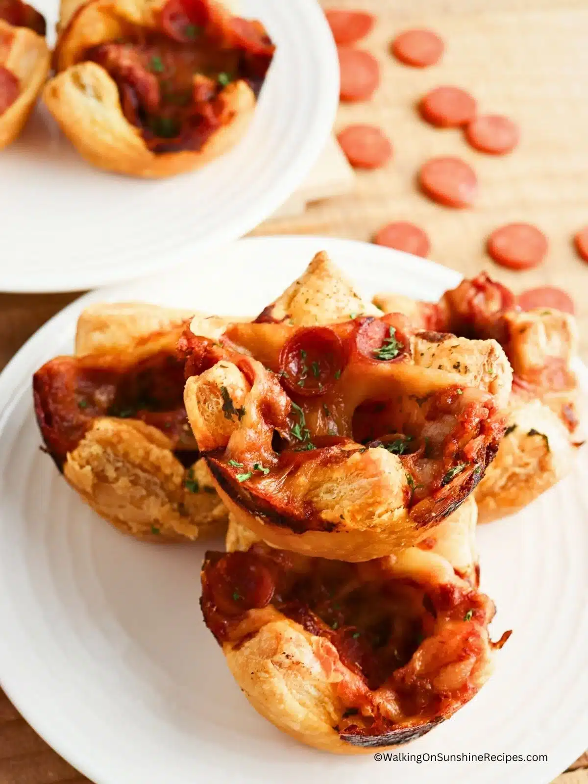 Mini Pizza Puffs on a white plate with mini pepperonis scattered on the cutting board
