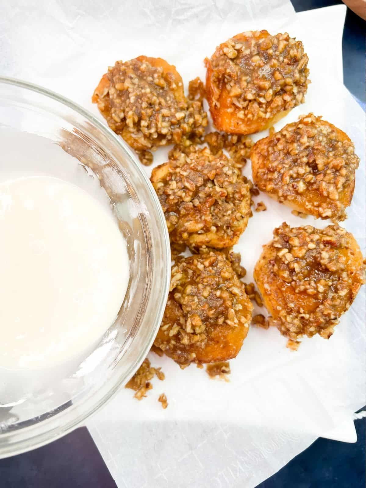 Powdered sugar glaze ready to pour on top of fresh baked pecan cinnamon rolls.