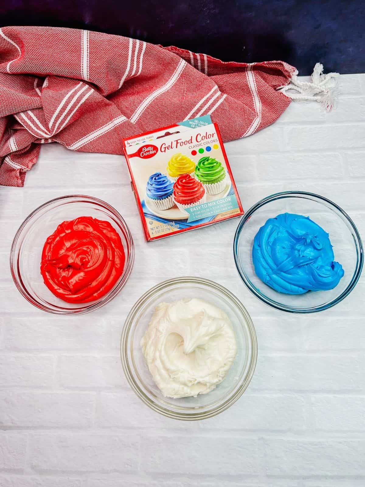 red, white and blue frosting in bowls.