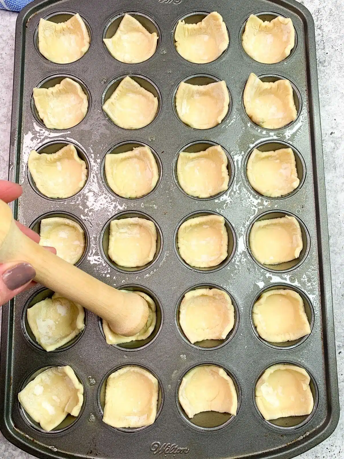tamper tool pressing pastry into mini muffin pan