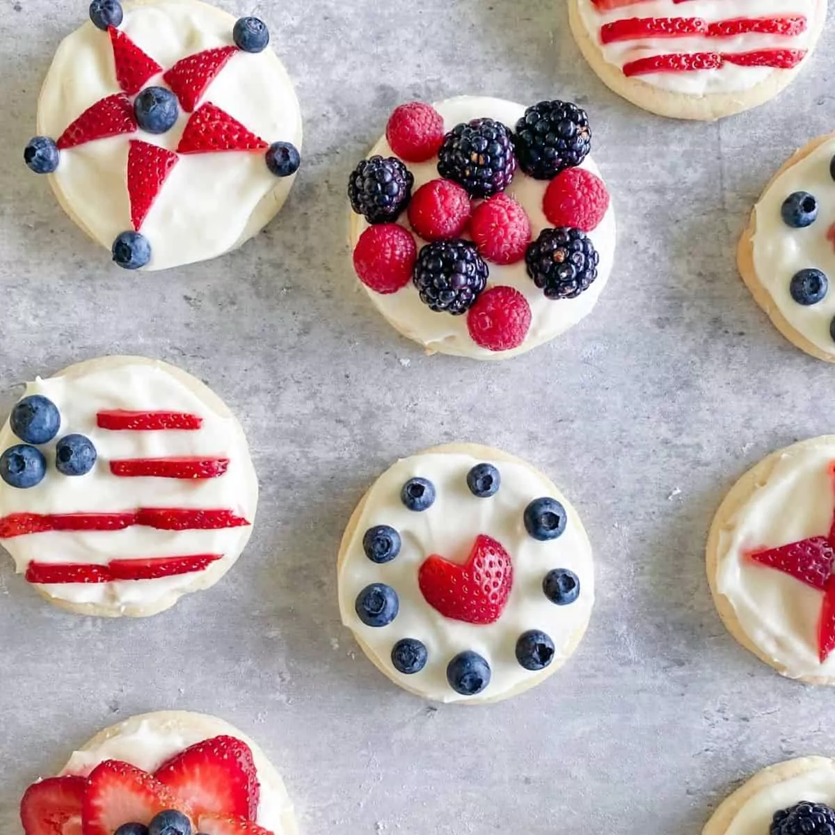 soft cookies decorated with white frosting, strawberries and blueberries.