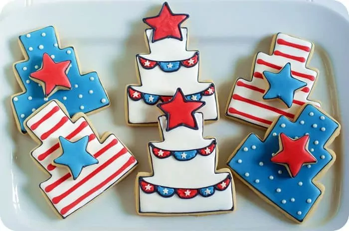 cut out cookies in the shape of 3 tiered cakes decorated in patriotic colors.