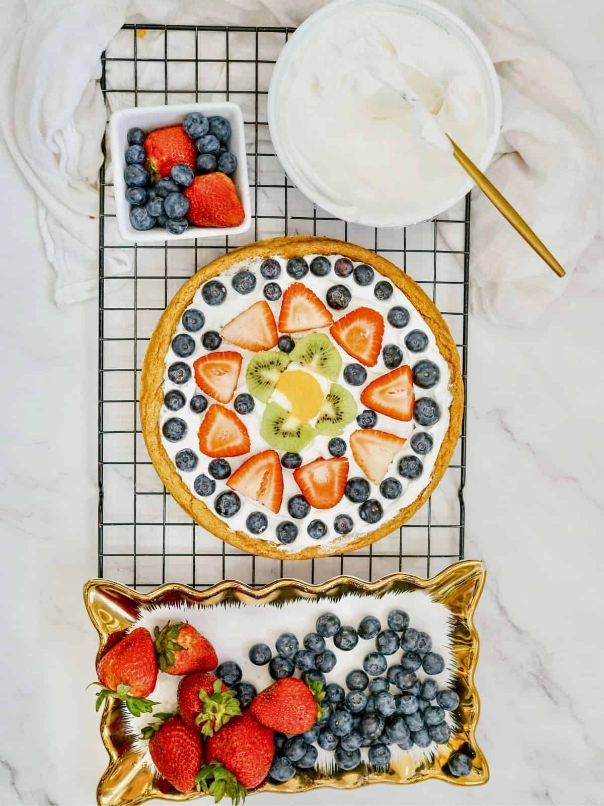 cookie pizza with whipped topping and mixed fruit.