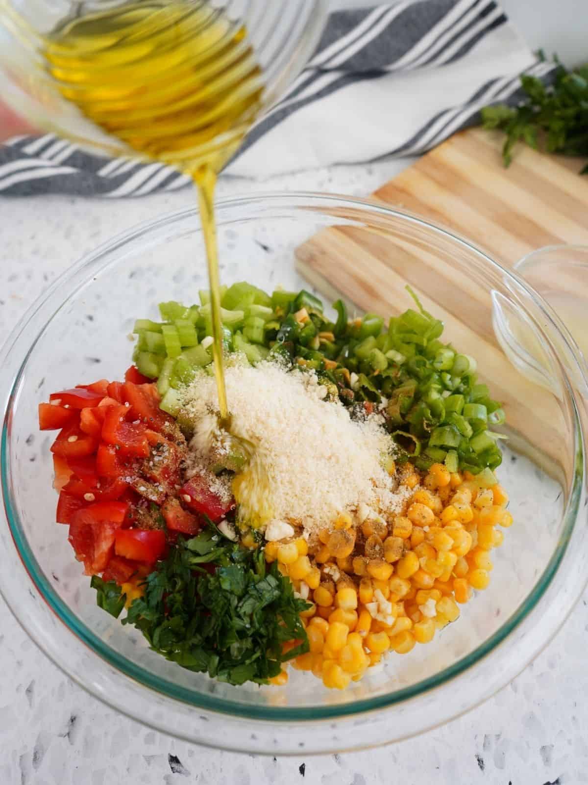 Add olive oil to bowl of corn salad ingredients.