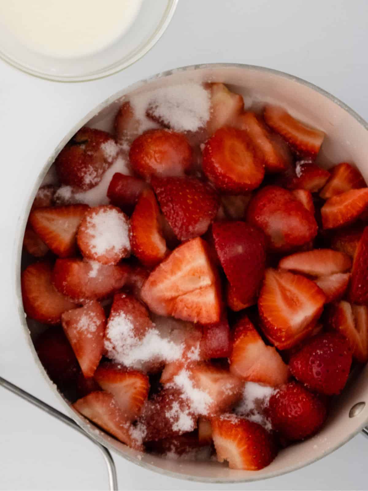 Add sugar and begin to mash strawberries.
