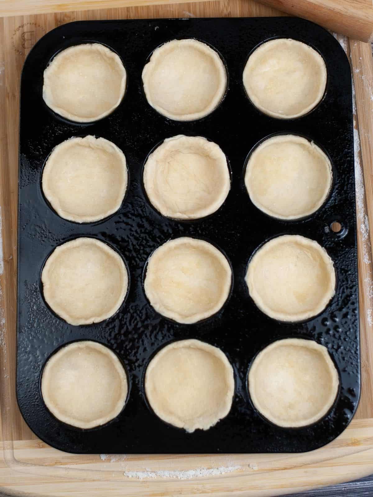 pie dough formed into muffin pan.