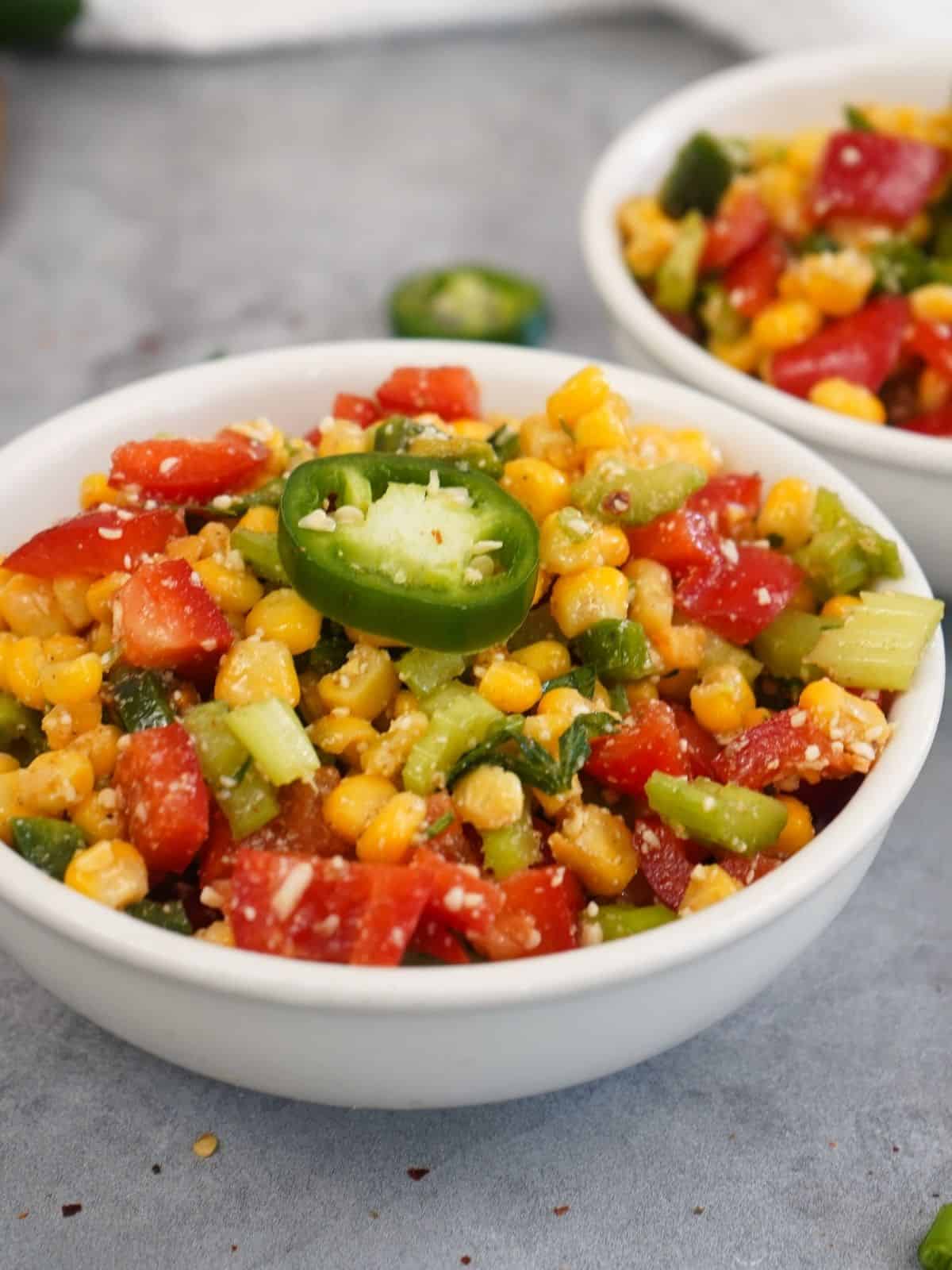 bowl of fiesta corn salad with sliced jalapeno pepper on top.