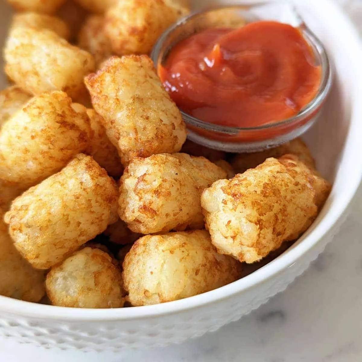 tater tots in bowl with ketchup.